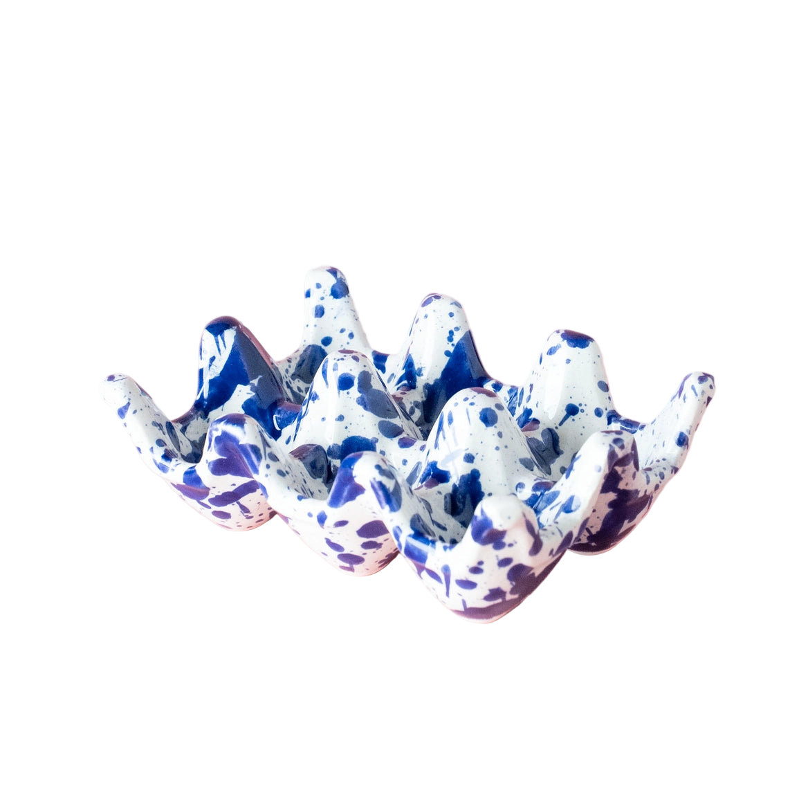 Speckled blue and white ceramic egg holder on a pink background