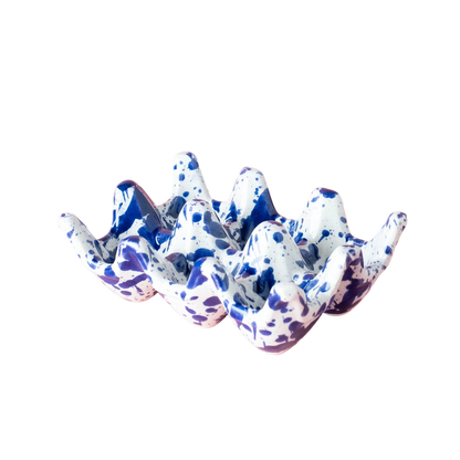 Speckled blue and white ceramic egg holder on a pink background
