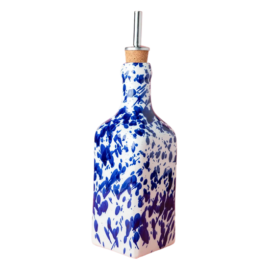 Blue and white ceramic oil bottle with a cork stopper on a pink background